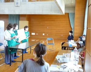 体育館で3人の発表を複数人が聞いている自主活動の様子の写真