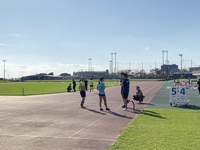 コースの端に立ち会話をしている4人の陸上選手たちの写真