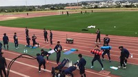 コートの端で筋トレなどをしているサッカー選手たちの写真