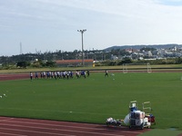 ひねりを入れたウォーミングアップをしているサッカー選手たちの写真