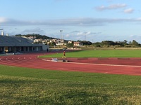 グラウンドを歩いている男性の陸上選手の写真