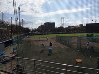 グラウンドの端で投球の練習を行っている野球選手たちの写真