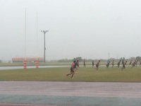 雨の中ラグビー選手たちがコートを走り回っている様子の写真