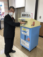 返却ポストに本を返却して見せている知花教育長の写真