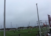曇り空の下練習試合を行っているサッカー選手たちの写真