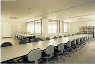 白い長机が部屋を横断するように一列に並べてある、ふれあい交流館の団体室の写真
