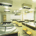 調理台が等間隔に設置されており、コンロの真上の天井に換気扇が取り付けられている、ふれあい交流館の調理実習室の写真
