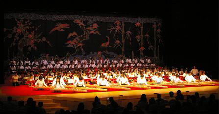 舞台上で大勢の人たちが琴を弾いている鳳ホールで行われた子ども芸能祭の様子を撮影した写真