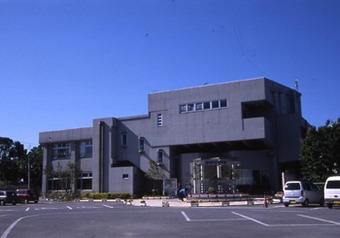 読谷村立図書館正面側の写真。駐車場に車が2台駐車している。