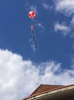 大空にあげられたアドバルーンの写真。バルーンの下には「誕生日本一人口の多い読谷村」の文言が確認できる