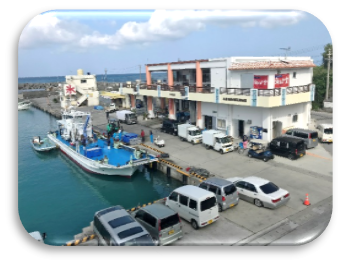たくさんの車と一艘の船に建屋が写った都屋漁港の写真